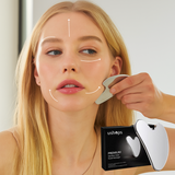 Woman using a facial massager on her face with a product box in the foreground.